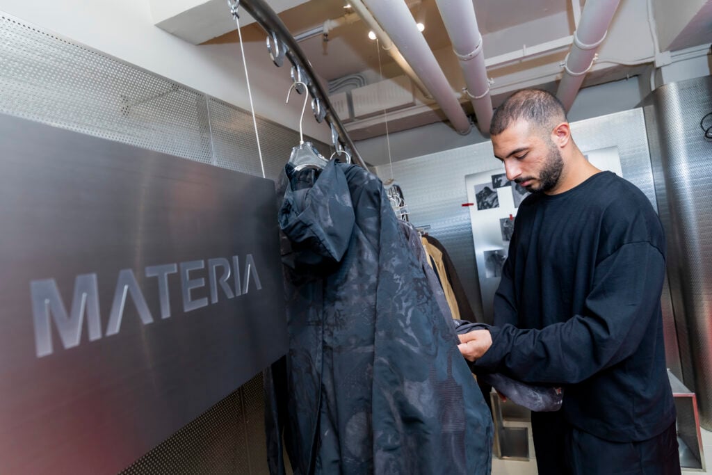 Fashion designer Francesco Saverio Matera standing beside MATERIA outerwear designs at the Future Threads exhibition in Hong Kong. 