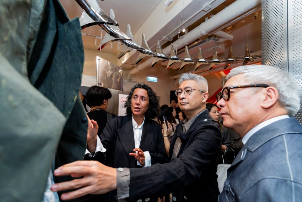 Sara Sozzani Maino speaking with visitors while examining garments at the Future Threads exhibition in Hong Kong.
